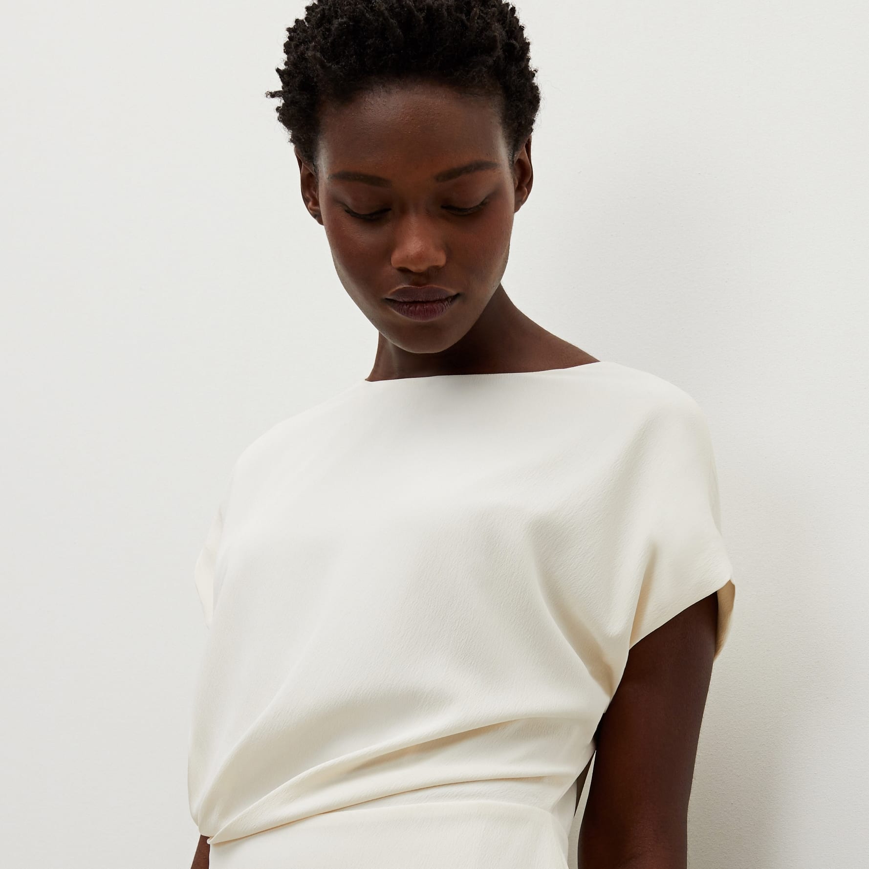 Side image of a woman standing wearing the Nejvi Top in alabaster | Exclude