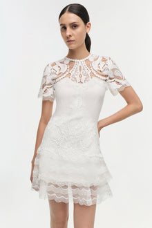 White lace dress with short sleeves, ornate paisley pattern, and tiered scalloped hem.