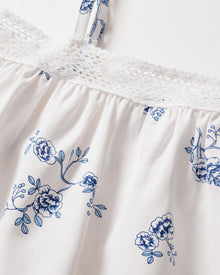 Close-up of the Girls Twill Lily Nightgown in Indigo Floral by Petite Plume, showcasing a delicate vintage blue floral pattern with an elegant white lace trim at the top edge and thin straps.