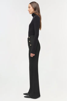 Black tailored trouser with gold button details at waist, worn with black turtleneck, side view on model.