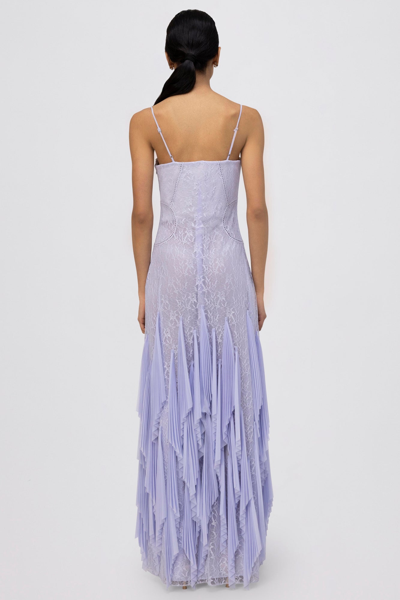 Lavender lace gown with spaghetti straps, fitted bodice, and pleated handkerchief hem skirt, shown from back view.