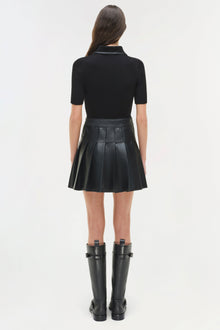 Black mini dress with ribbed knit collared top and pleated leather skirt, worn with black knee-high boots.