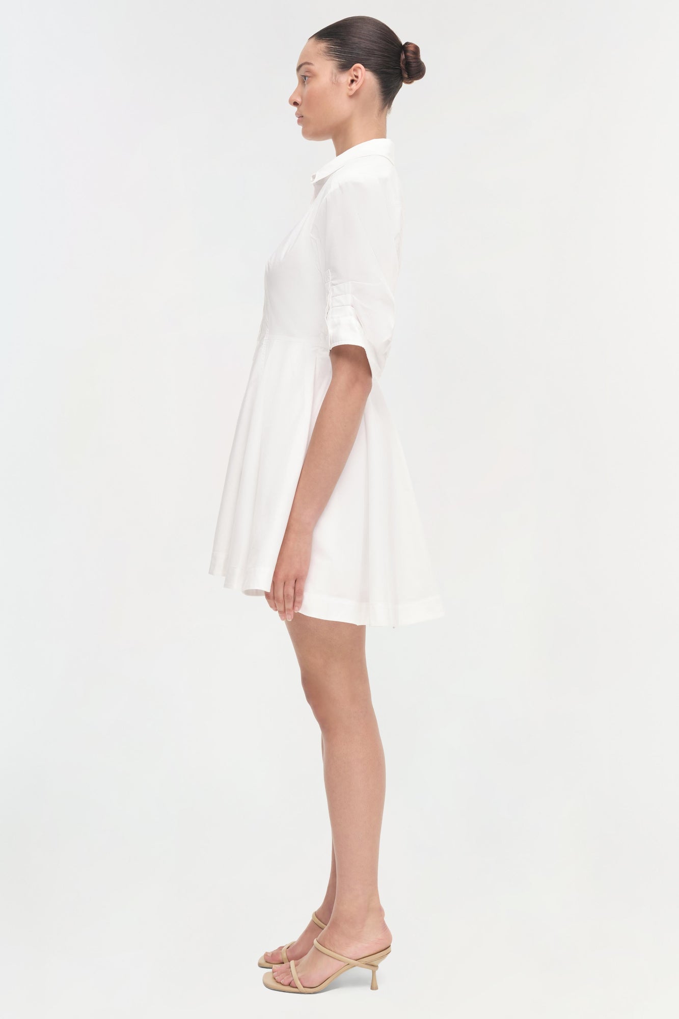 White short-sleeve shirt dress with a-line skirt, shown on model in side profile.
