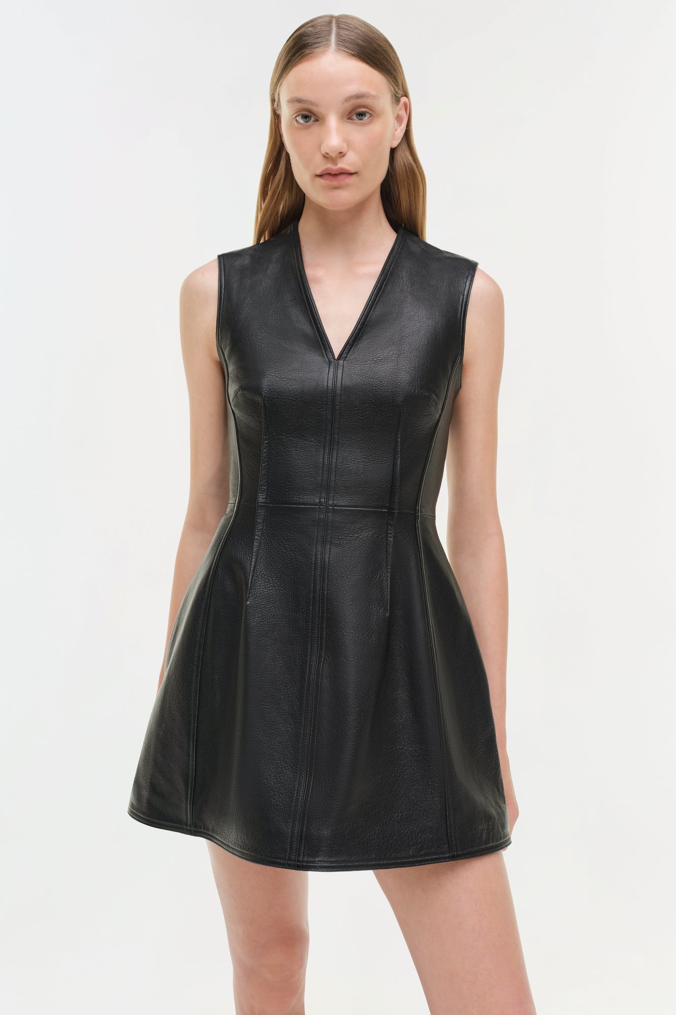 Black leather sleeveless mini dress with V-neckline and fitted bodice on model.