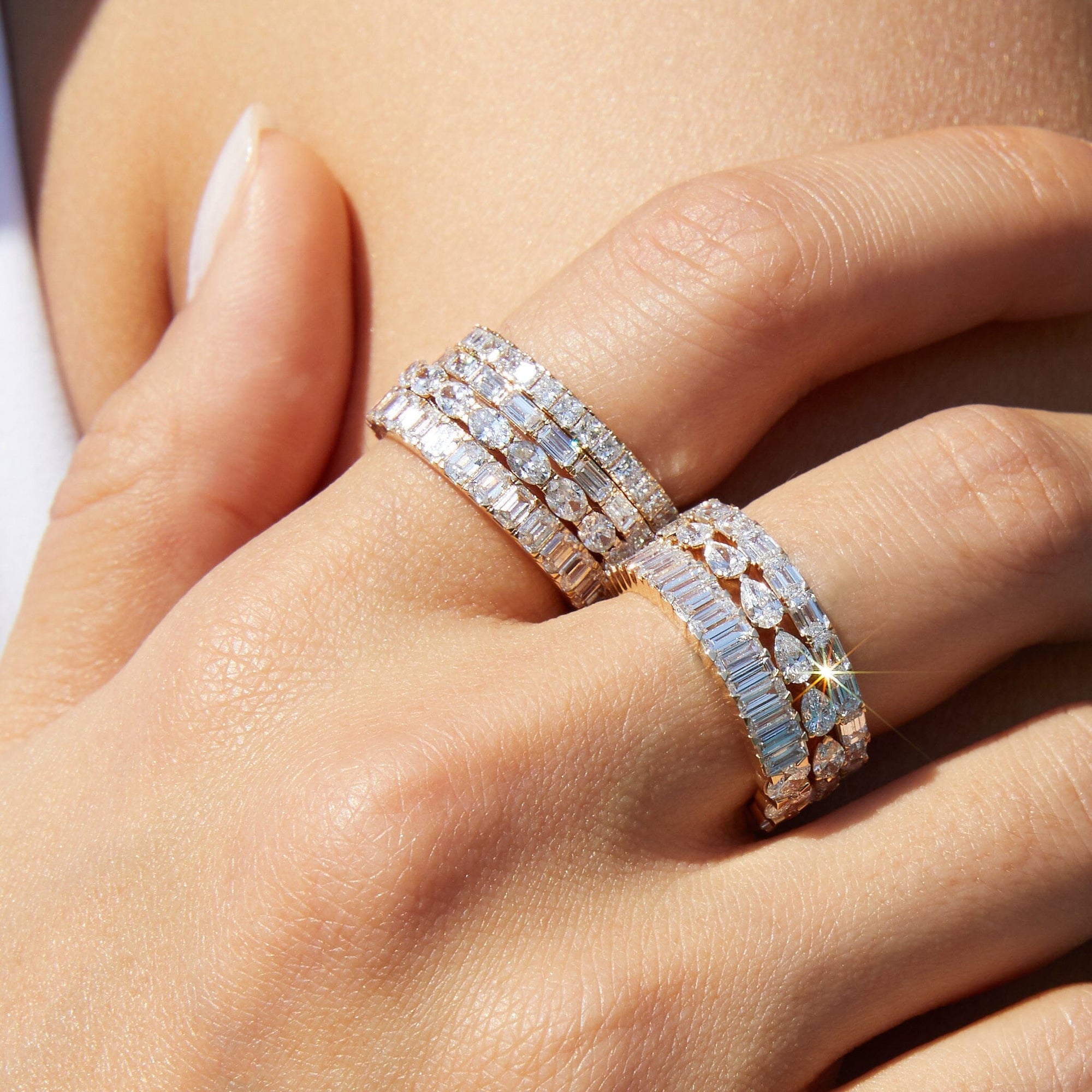 Lifestyle Model Close-up of a woman's hand resting near her neck, wearing multiple gold and diamond eternity rings.
