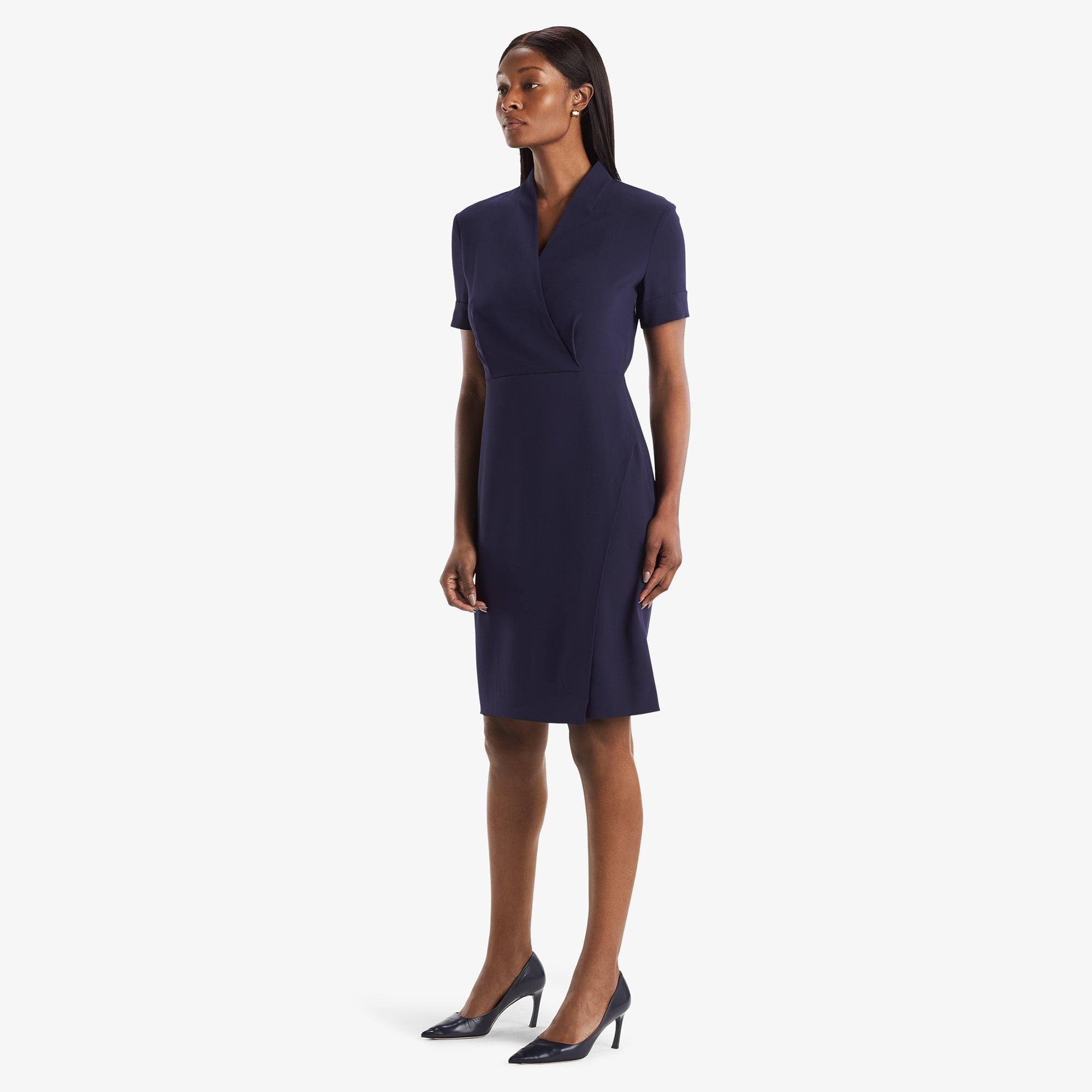 Side image of a woman standing wearing theTory Dress in dark iris