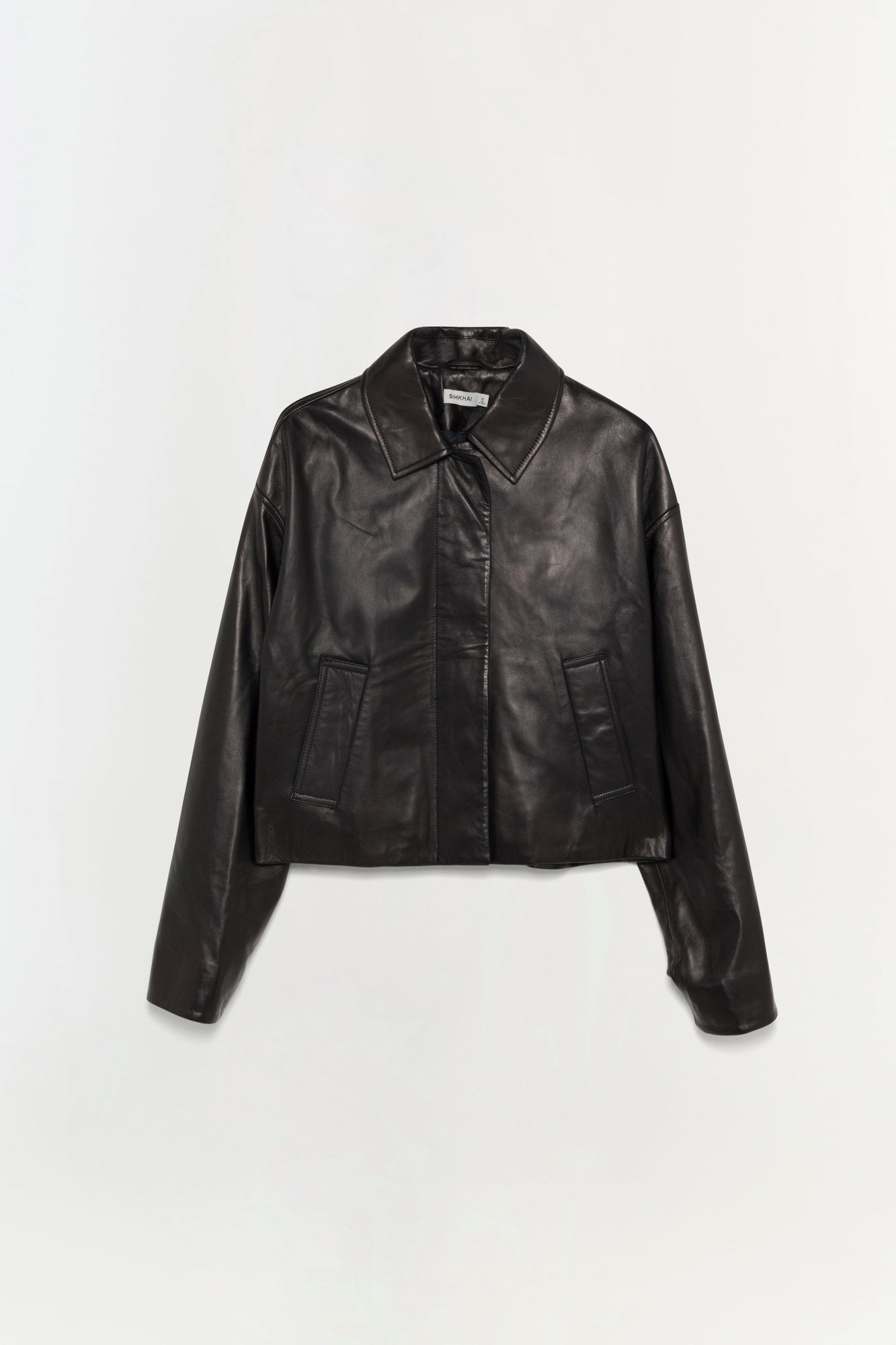 Black leather jacket with collared neckline, button front closure, and two front pockets displayed on neutral background.