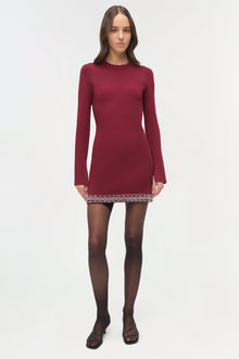 Burgundy knit mini dress with long sleeves and beaded trim detail at hem, modeled with black tights.