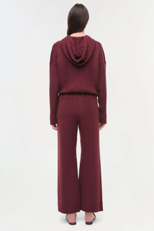 Woman wearing burgundy wide-leg pants with a matching textured hooded top, shown from back.