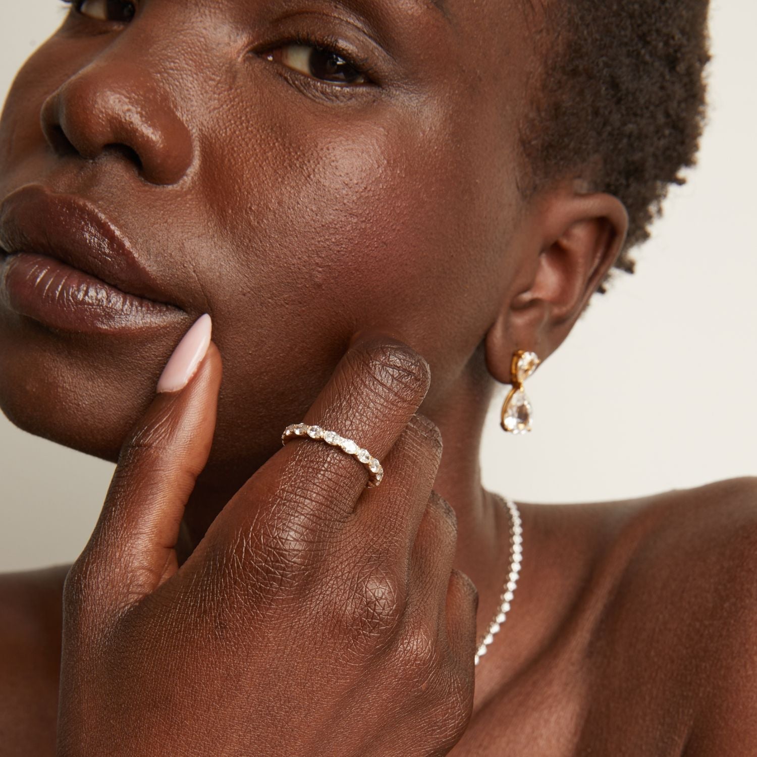 Model. Close-up of a woman wearing a ring and earring, with a neutral background