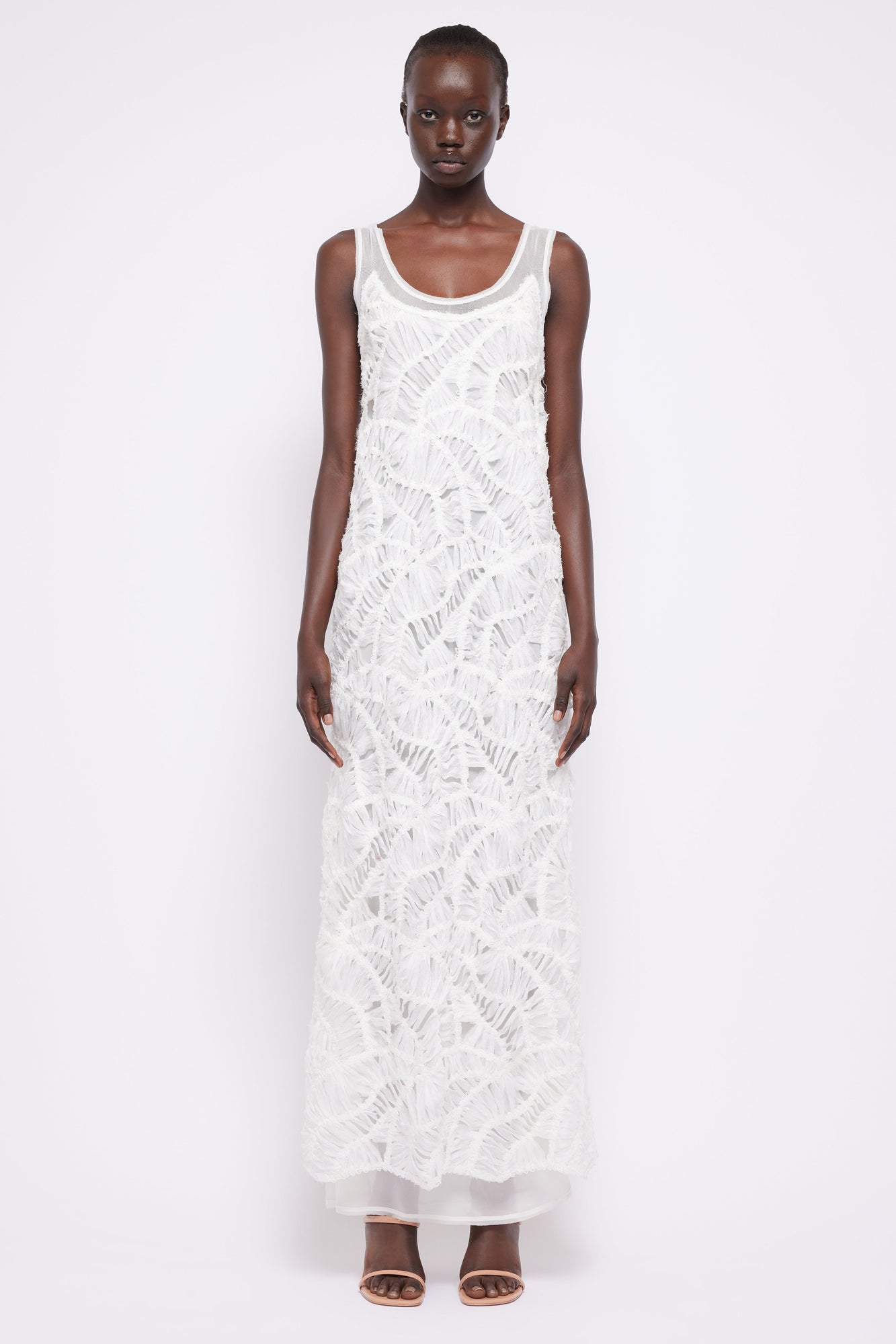White sleeveless maxi dress with textured fringe pattern and scoop neckline.