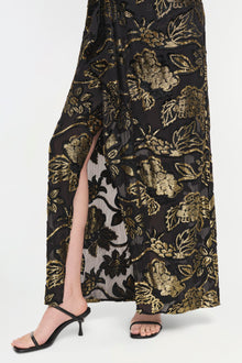 Black gown with gold floral embroidery and front slit, paired with black strappy heeled sandals.