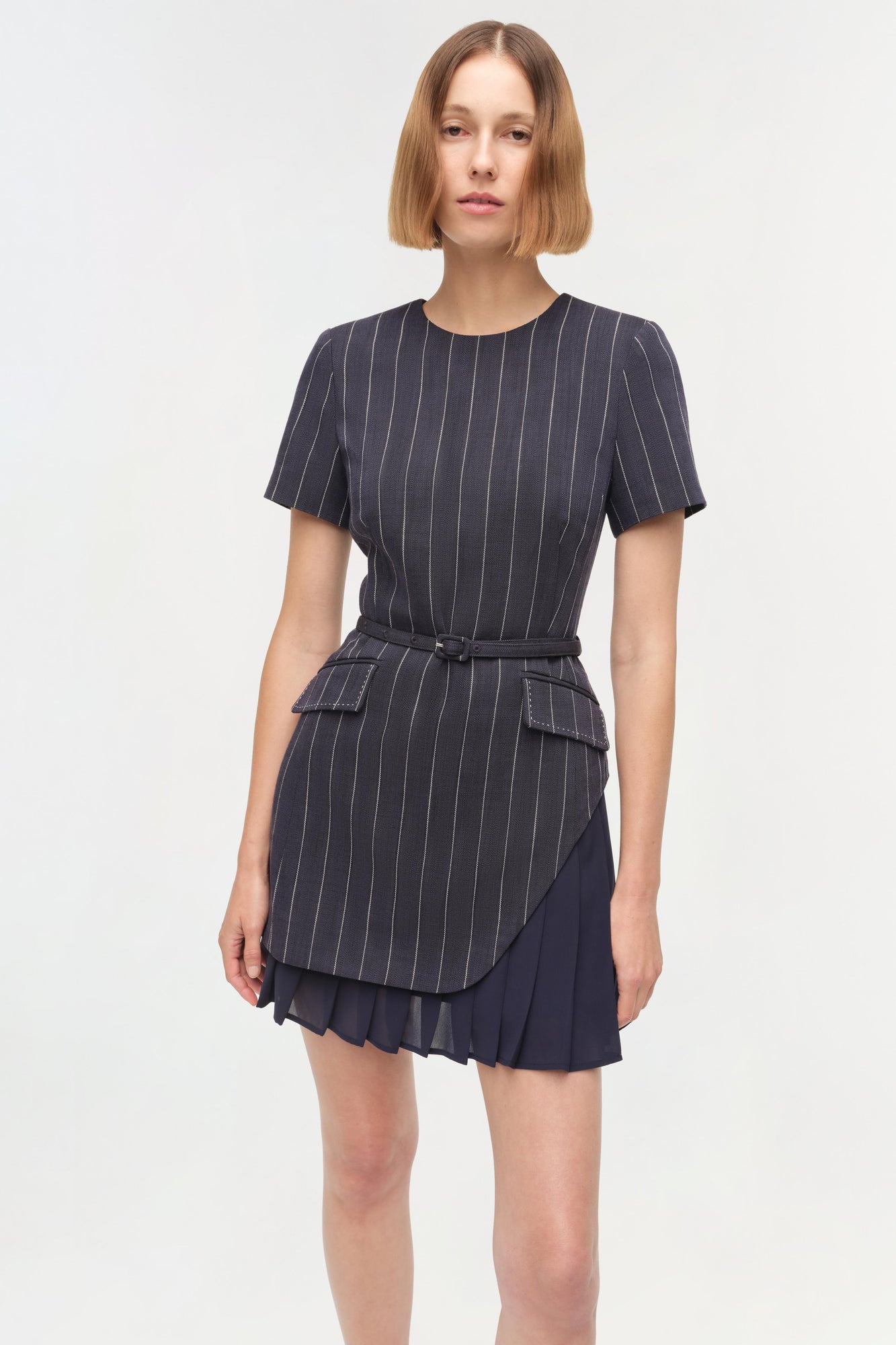 Navy pinstripe mini dress with short sleeves, belt at waist, and pleated skirt overlay.