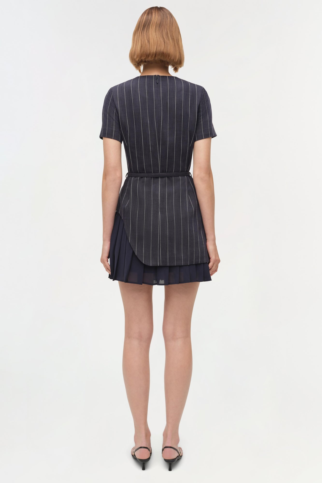 Navy pinstriped mini dress with short sleeves, belt at waist, and layered skirt hem, shown on model from back.