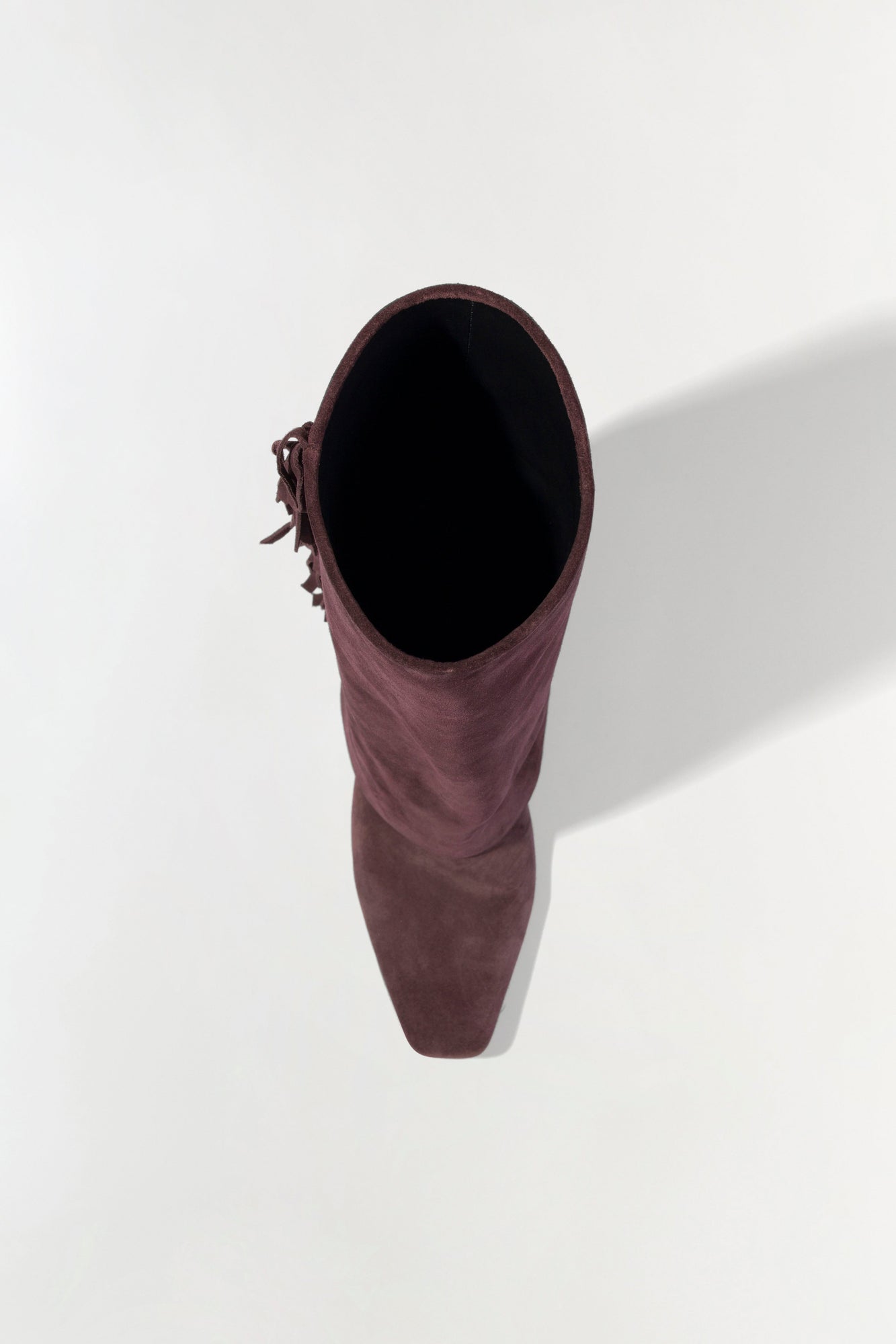 Burgundy suede boot with fringe tassel detail on the side, shown from top view.