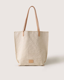The graf lantz Hana Canvas Tote showcases durable beige cotton canvas, brown leather handles, and a small leather logo patch near the bottom, all set against a plain white background.