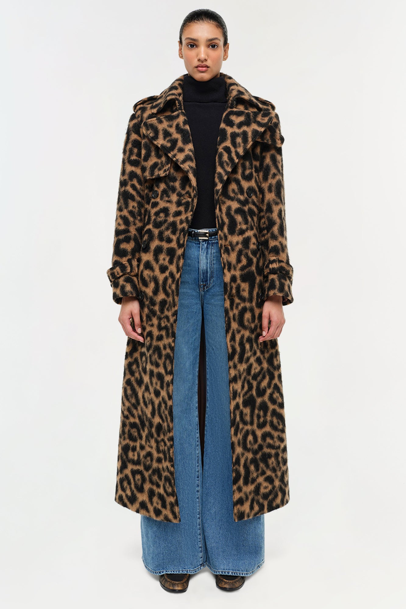 Leopard print wool overcoat with notched collar, worn over black turtleneck and blue jeans.