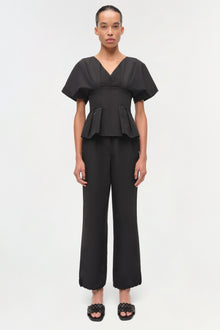 Black cotton faille top with V-neckline, short puffed sleeves, and peplum waist detail.