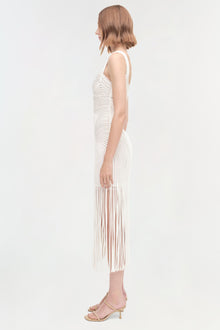 White sleeveless dress with pleated skirt and wavy texture pattern, shown on model from side view.
