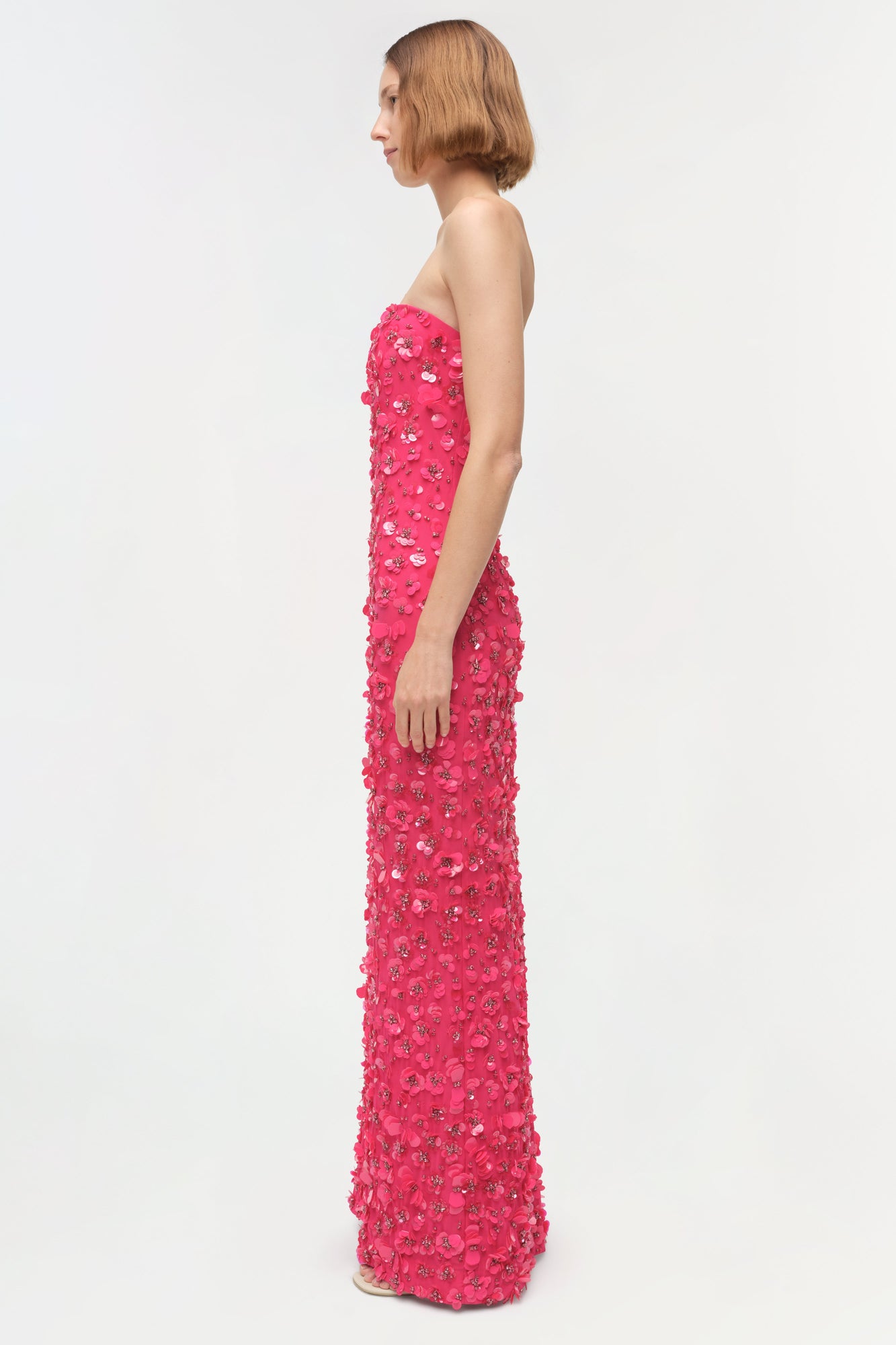 Strapless pink gown with sequin and beaded embellishments throughout, shown on model in side profile.