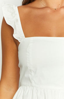 Close-up of the white ruffled shoulder strap, square neckline, and fitted bodice with a seam of a mini dress