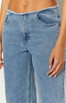 Detail shot of the raw-edge waistband and curved front pockets on mid-wash blue denim jeans
