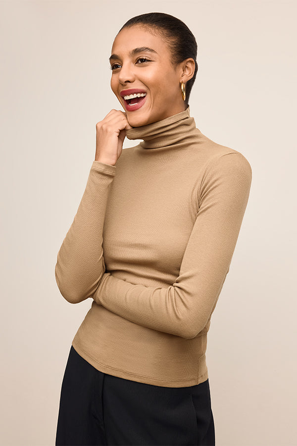 Woman wearing a beige turtleneck sweater against a beige background | Exclude