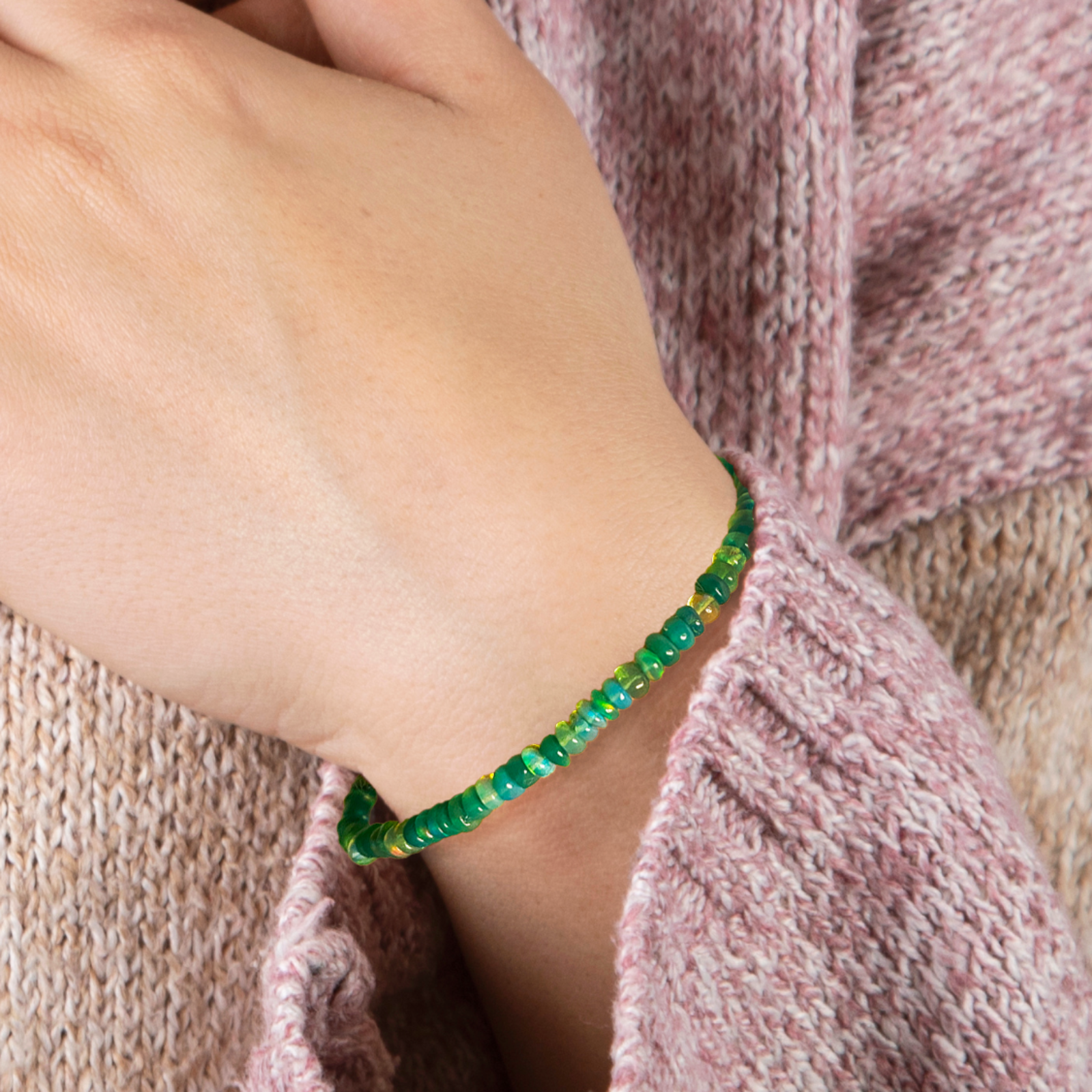 Shimmering beaded bracelet made of smooth opals in shades of green on a gold linking lobster clasp.