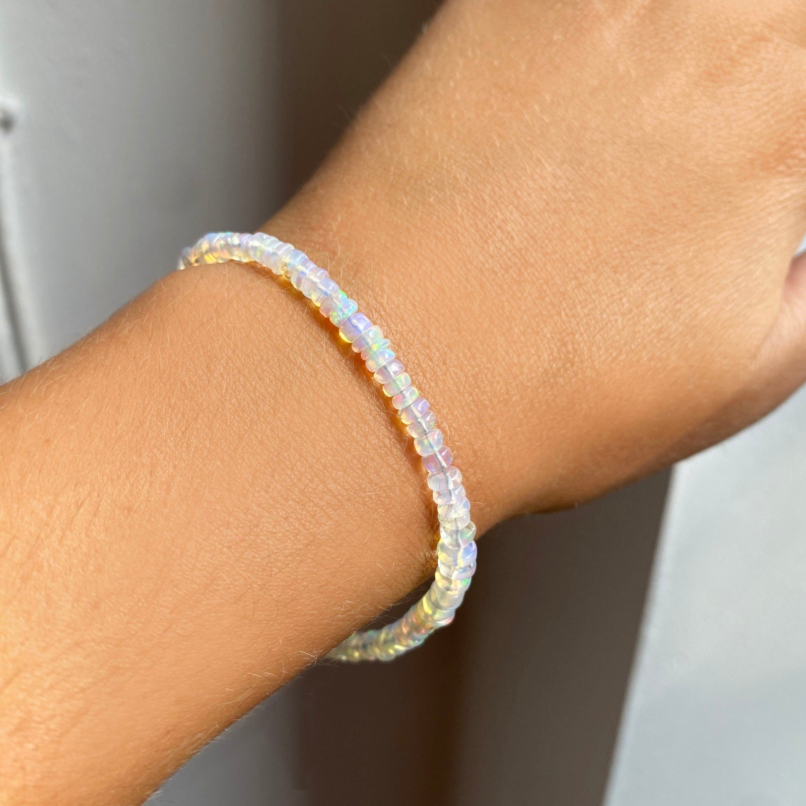 Shimmering beaded bracelet made of faceted opals in shades of milky white and clear on a gold linking lobster clasp.