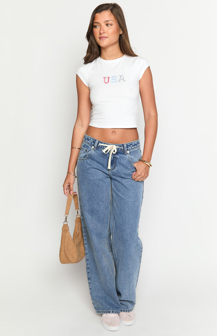 Mid wash denim jeans with a cream tie waist and a relaxed wide-leg fit
