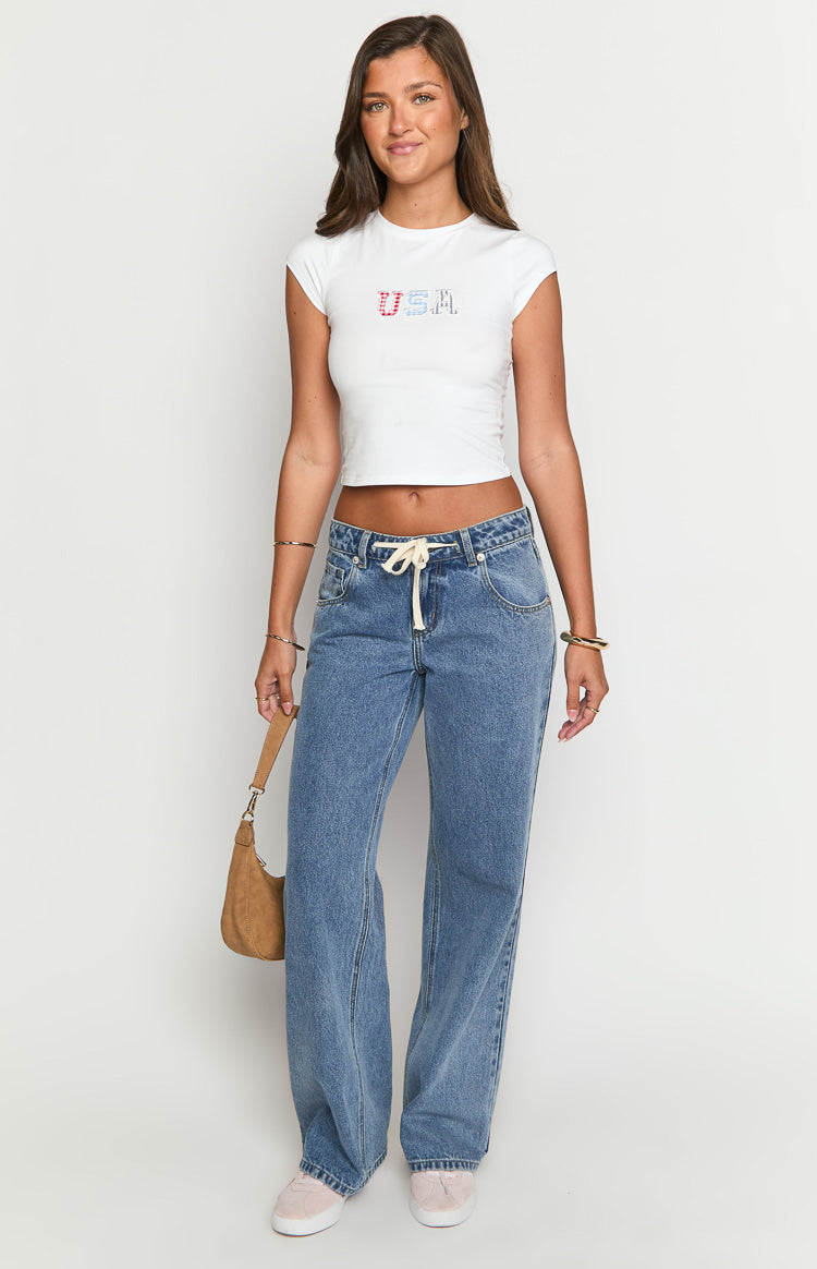 Mid wash blue denim jeans with a cream tie waist and relaxed wide leg fit