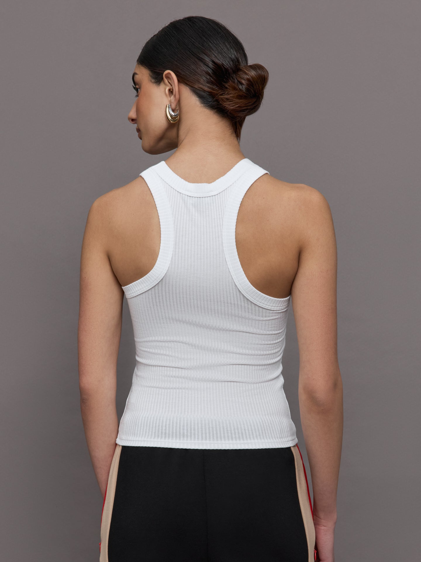 Model wears a white high neck ribbed jersey tank. 