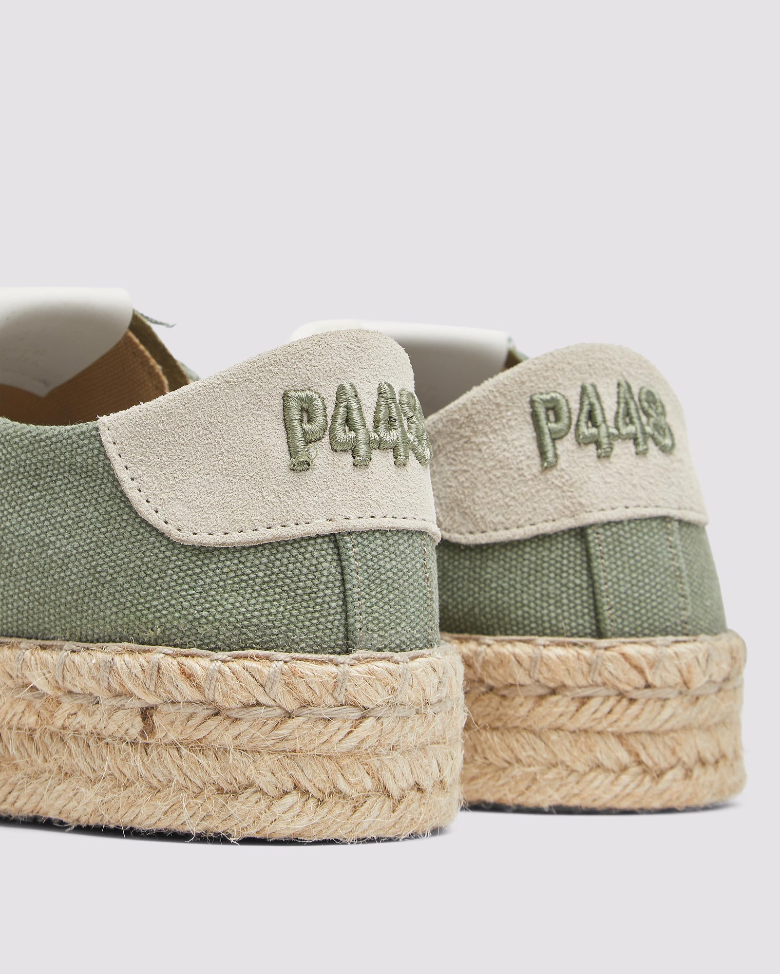 Back view of P448 green canvas low-top sneaker with tan recycled suede heel tab, showing the green canvas upper and organic jute sole.