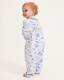 The Baby's Twill Cambridge Romper in Chalet Toile is a white long-sleeve, full-length onesie with blue alpine scene prints and blue piping on the collar, cuffs, and front placket.