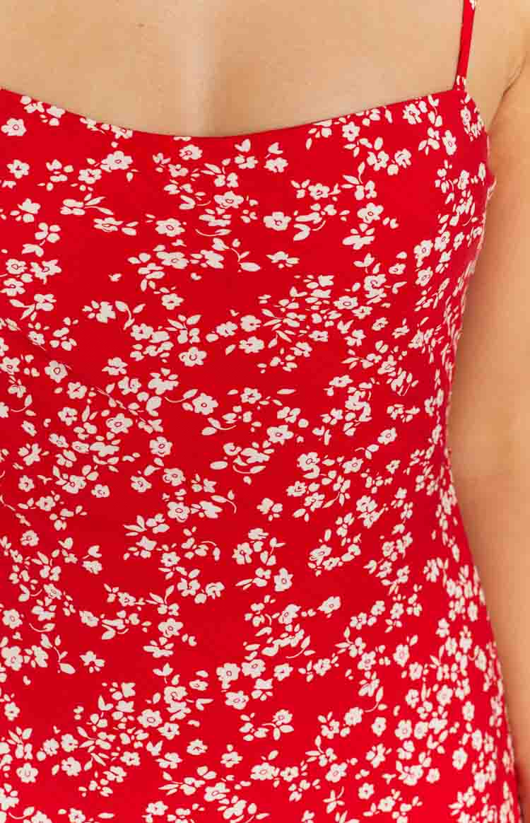 Close-up of the red midi dress fabric with scattered white floral print and a thin spaghetti strap