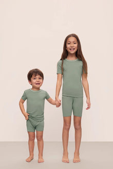 Model is wearing Kids TENCEL Modal Unisex Short PJ Set in Eucalyptus/Ivory