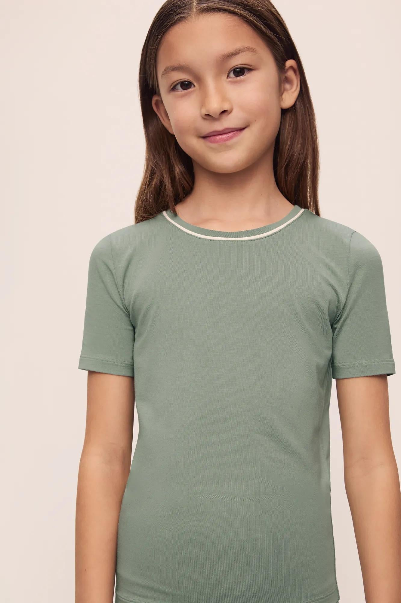 Model is wearing Kids TENCEL Modal Unisex Short PJ Set in Eucalyptus/Ivory