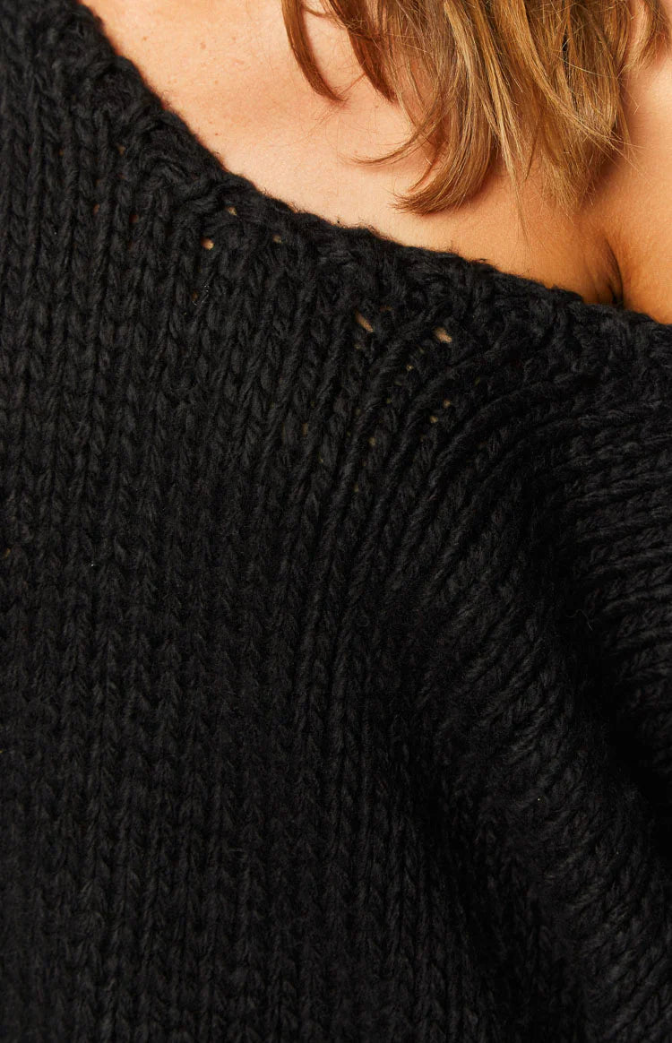 Black chunky knit sweater worn off-shoulder with a relaxed fit