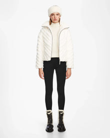 A woman wears the Rudsak ANASTASIA - 8124804 Iceland womens down puffer in white, styled elegantly with a matching hat.
