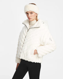 Dressed in the Rudsak ANASTASIA - 8124804 Iceland faux fur jacket and matching headband, this person stands confidently with one hand in their pocket, black pants completing the ensemble against a light background.