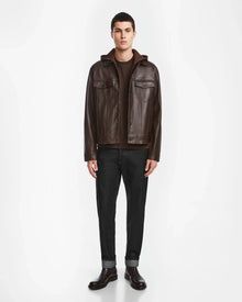 A man faces forward wearing the Rudsak AREN - 6124580 Espresso mens leather shirt jacket over a brown shirt, black cuffed pants, and brown shoes against a plain white background.