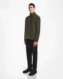 A young man stands against a white background wearing the Rudsak BECK - 6524538 Army men’s fleece pullover with vegan leather trims, paired with black pants and shoes. He faces forward, hands by his sides, with a neutral expression.