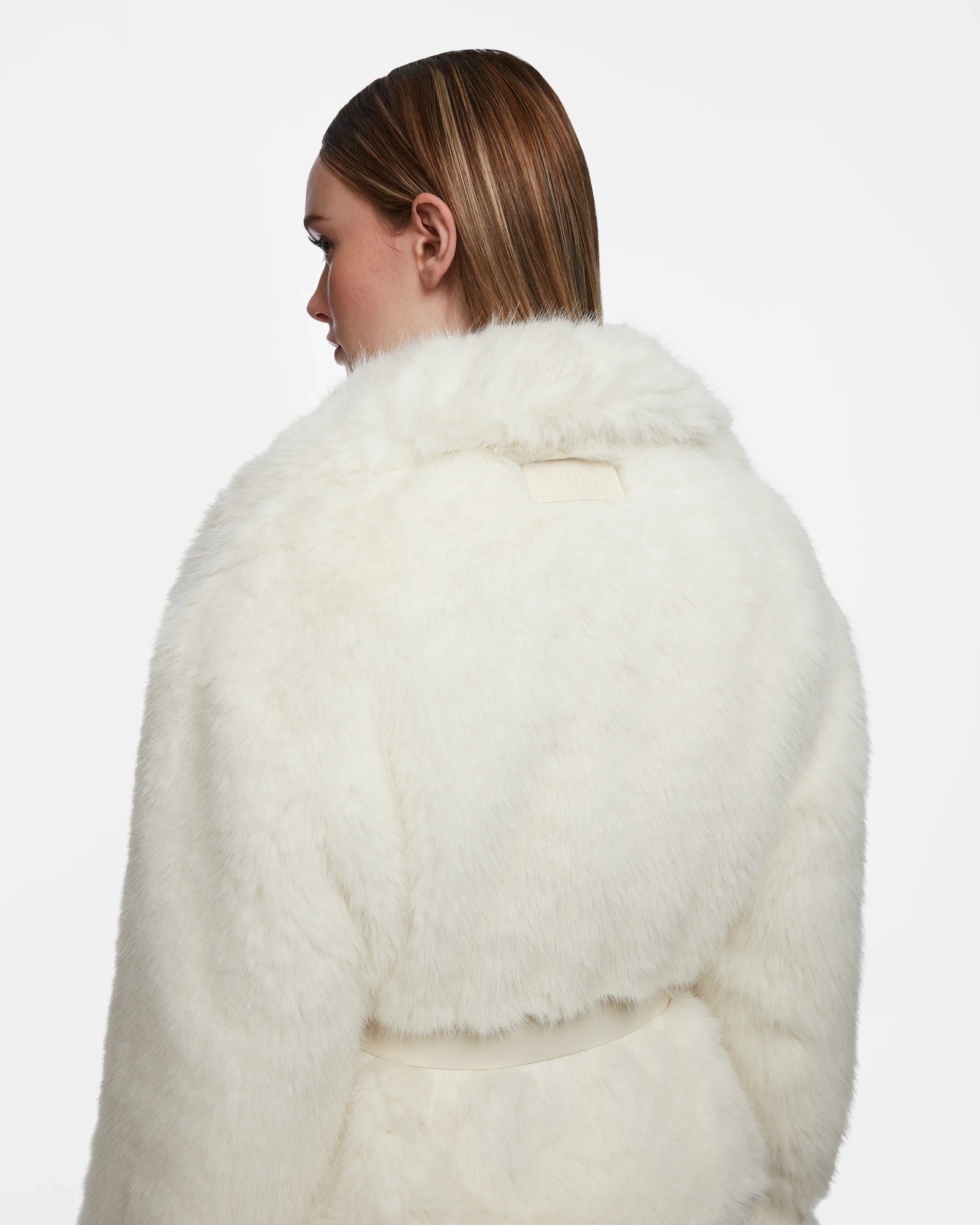 A woman with straight brown hair is shown from the back, modeling the Rudsak CHLOE - L124564 Iceland women’s faux fur jacket with a wide collar and belt, set against a plain white background.