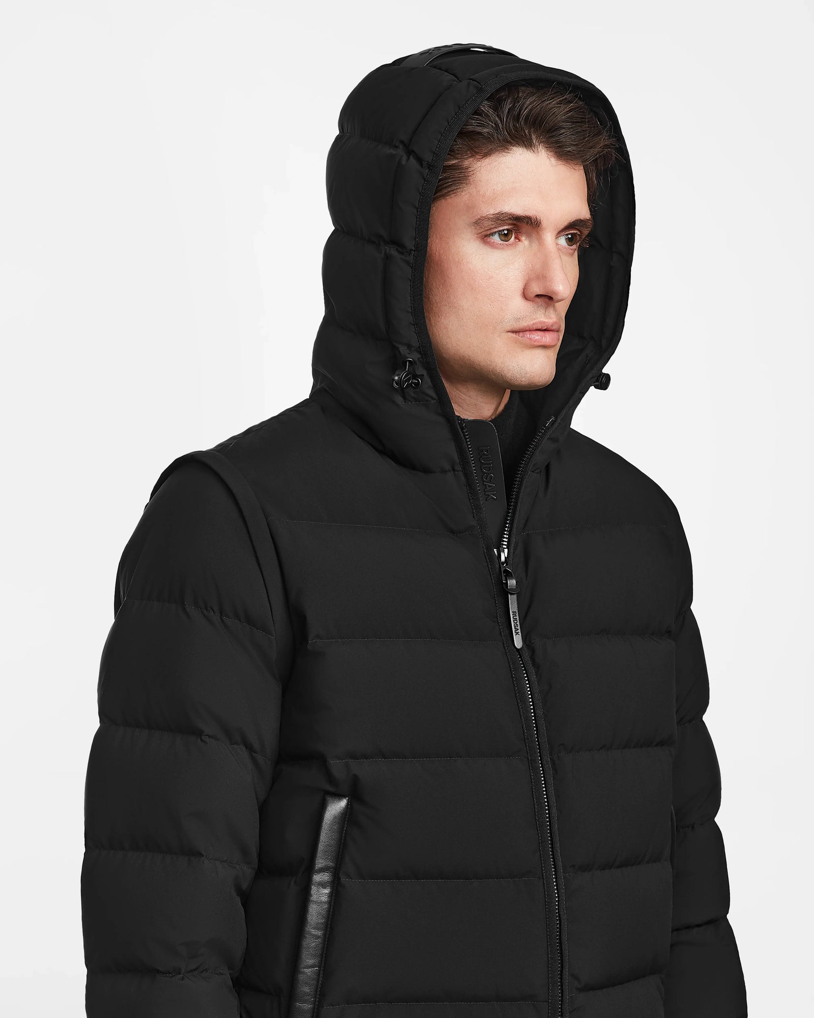 A man wearing the Rudsak DEMIAN M-R - M123504 Black, a mens down puffer coat crafted from recycled matte fabric.