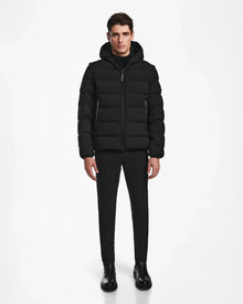 A man faces forward wearing the Rudsak DEMIAN M-R - M123504 Black mens down puffer, paired with black pants and boots, set against a plain white background.