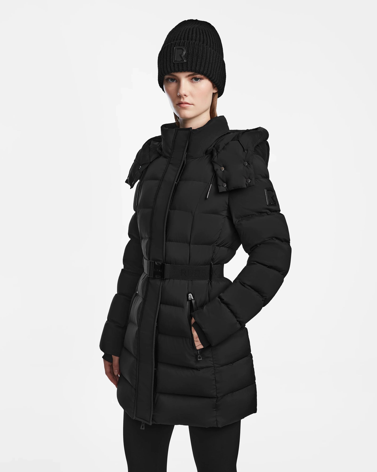 A woman in the Rudsak FRIDA M - L124524 Black mid-length down jacket with a removable hood.