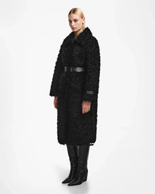 A woman in the Rudsak KAMILAH - 8124827 Black wool teddy coat, styled with a chic vegan leather waist belt.