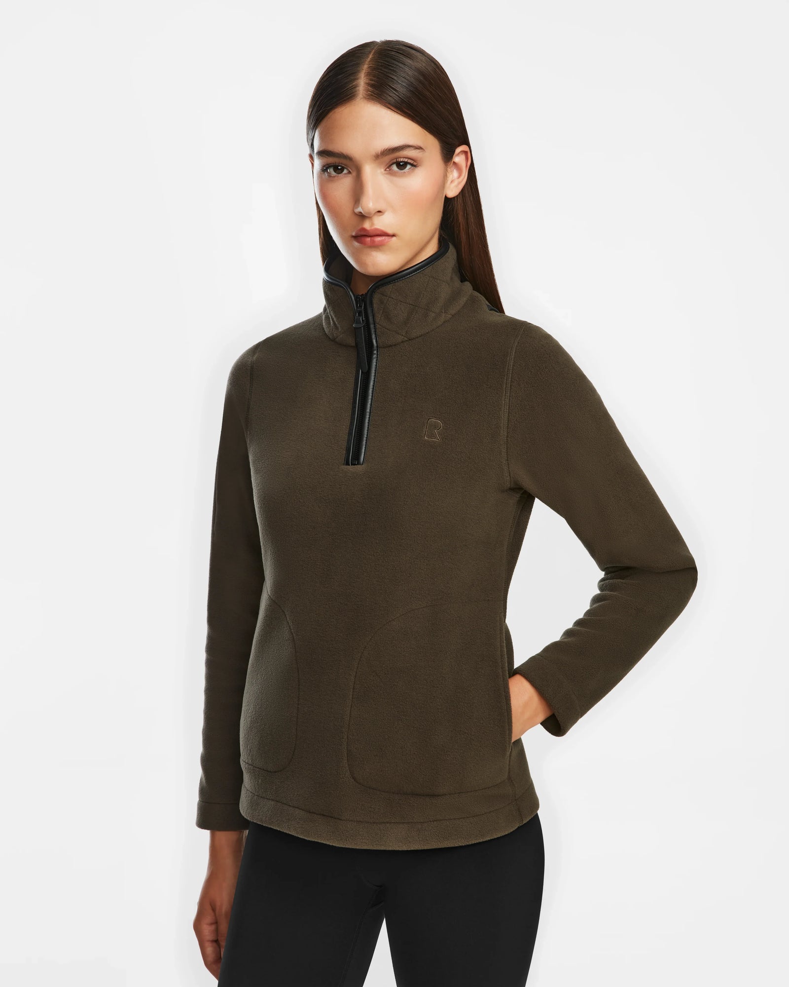 A woman with straight brown hair wears the Rudsak ORCHID - 8524616 Army women’s fitted half-zip pullover sweater, her left hand in her pocket, standing against a plain white background.