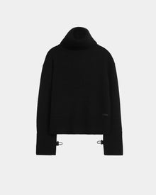 The PARMI - 8524608 Black by Rudsak is a womens knit turtleneck sweater featuring long sleeves, ribbed cuffs and hem, and two small metal buckles at the lower sides. Shown against a plain white background.