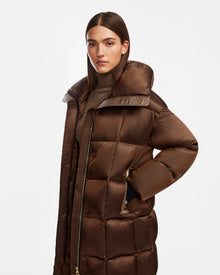 A woman with straight brown hair wears the Rudsak SASH R - 8124543 Antique Bronze long down puffer coat. The shiny brown winter outerwear features a high collar, visible zipper, and RDS-certified down against a plain white background.